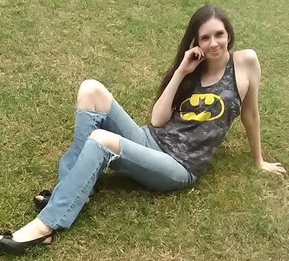 Woman sits on grass, wearing a Batman shirt.