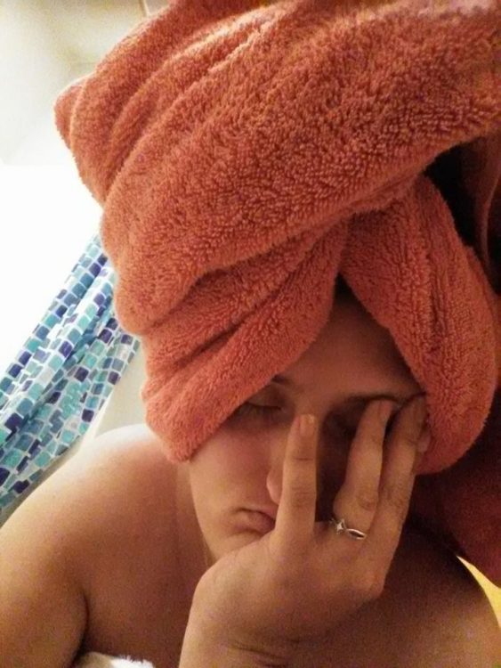 woman lying in bed after a shower with her hair wrapped in a towel