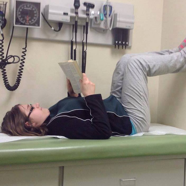 woman lying on a hospital bed reading a book