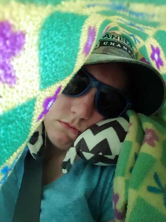 woman wearing sunglasses and covered in a blanket in the car