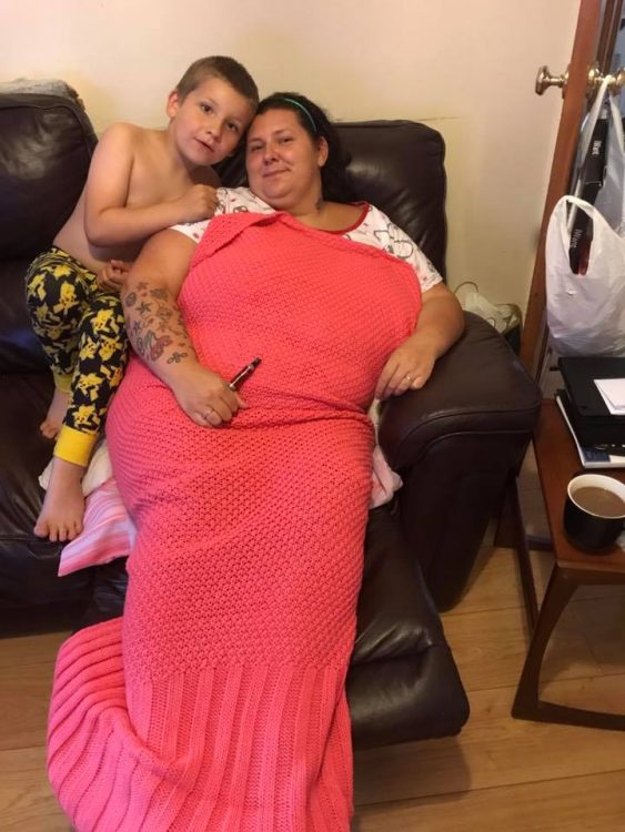 woman wrapped in a blanket sitting on the couch with her son