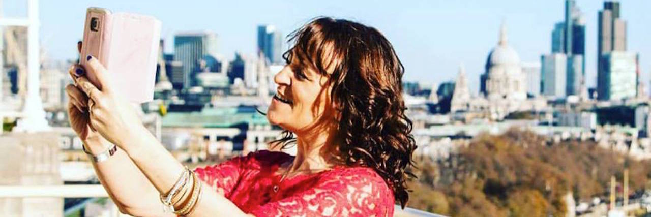 7 Things I Wish I Could Tell Myself When I First Became Ill The writer of the article taking a selfie in front of a city landscape.