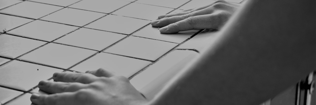 Painful and Uncomfortable Symptoms of Gastroparesis After Eating black and white photo of woman's hands gripping tiled counter