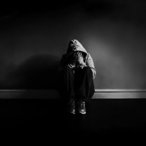 black and white photo of person in darkness looking depressed against wall Michelle Tuttle - MCT Photography