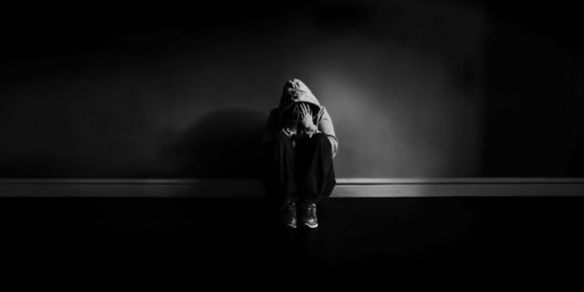 black and white photo of person in darkness looking depressed against wall Michelle Tuttle - MCT Photography