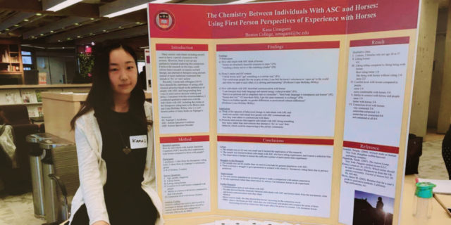 Kana with her conference presentation poster on the topic of Asperger's and horses.