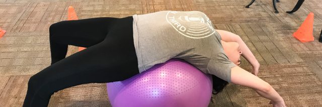 woman stretching her back on a balance ball