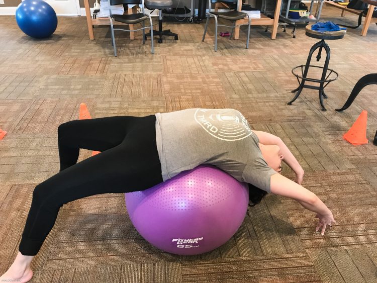 woman stretching her back on a balance ball