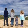 four kids standing on beach looking at ocean