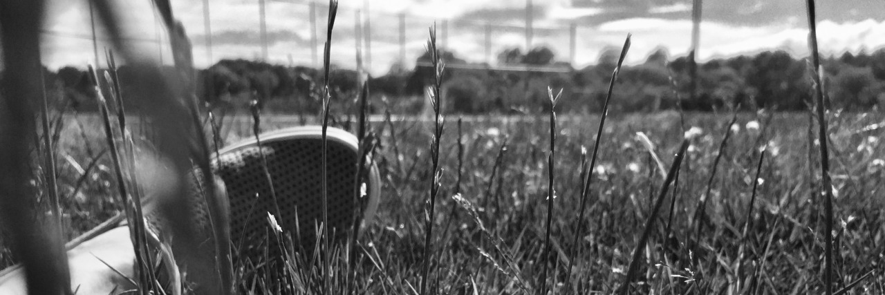 black and white photo of foot in grass with flower high contrast