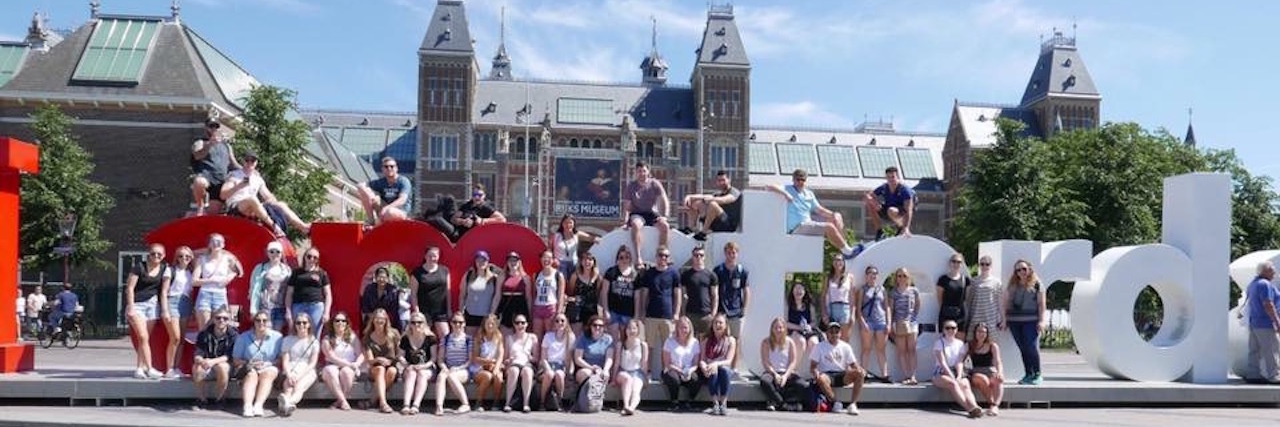 group sitting in front of the 'I amsterdam" sign