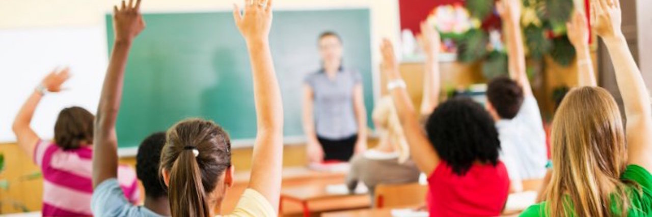 Teacher With Endometriosis Helps Student With Arthritis (JIA) students raising their hands in a classroom