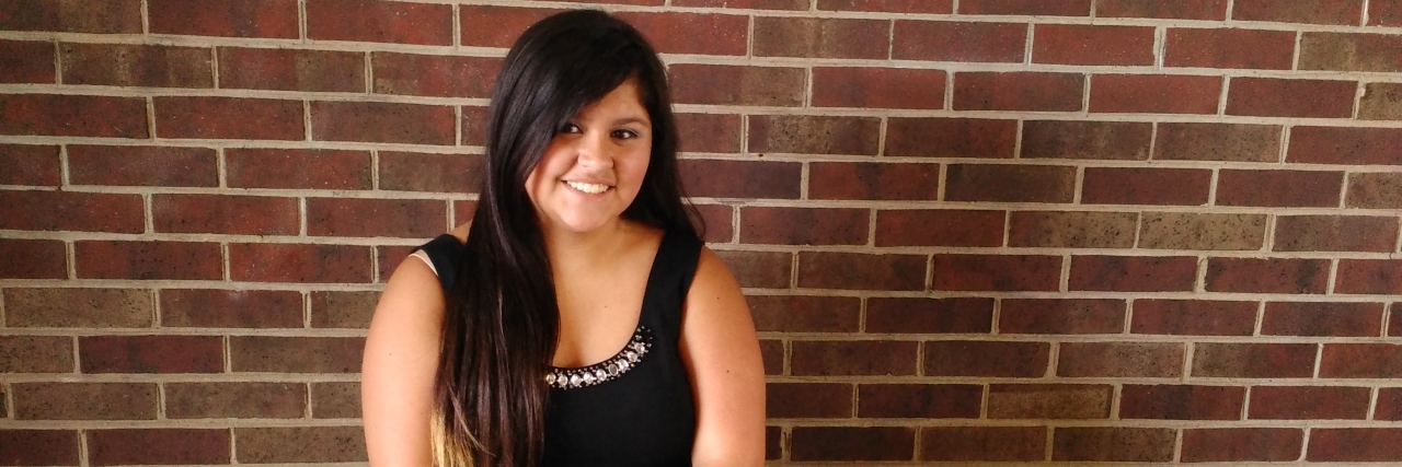 Entering High School With Mild Cerebral Palsy Heaven sitting on a bench against a brick wall at her school.