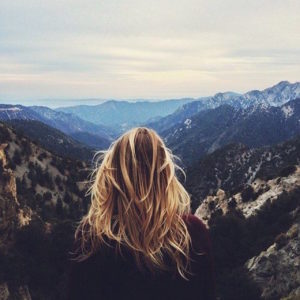 back of woman's head looking out over mountains and valleys