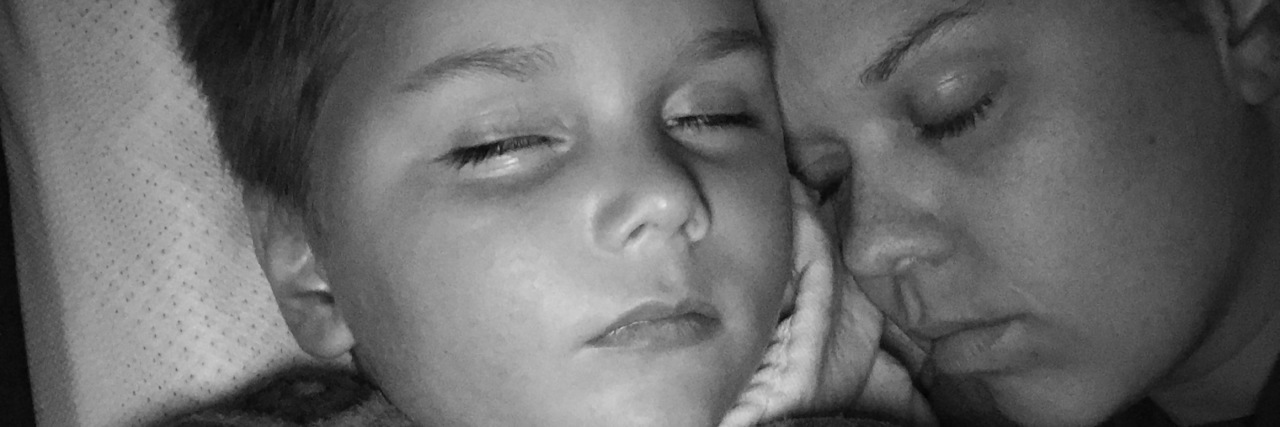 Black and white photo of mom laying with son, both have eyes closed