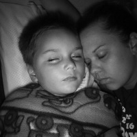 Black and white photo of mom laying with son, both have eyes closed