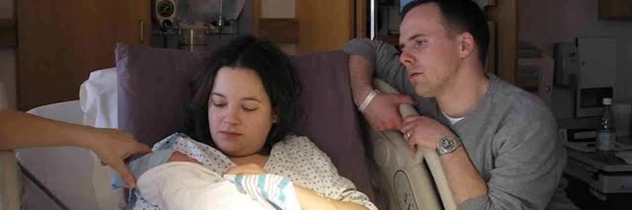 I Never Considered Ending My Pregnancy Because of Down Syndrome couple at hospital, mom in bed holding baby born with Down syndrome