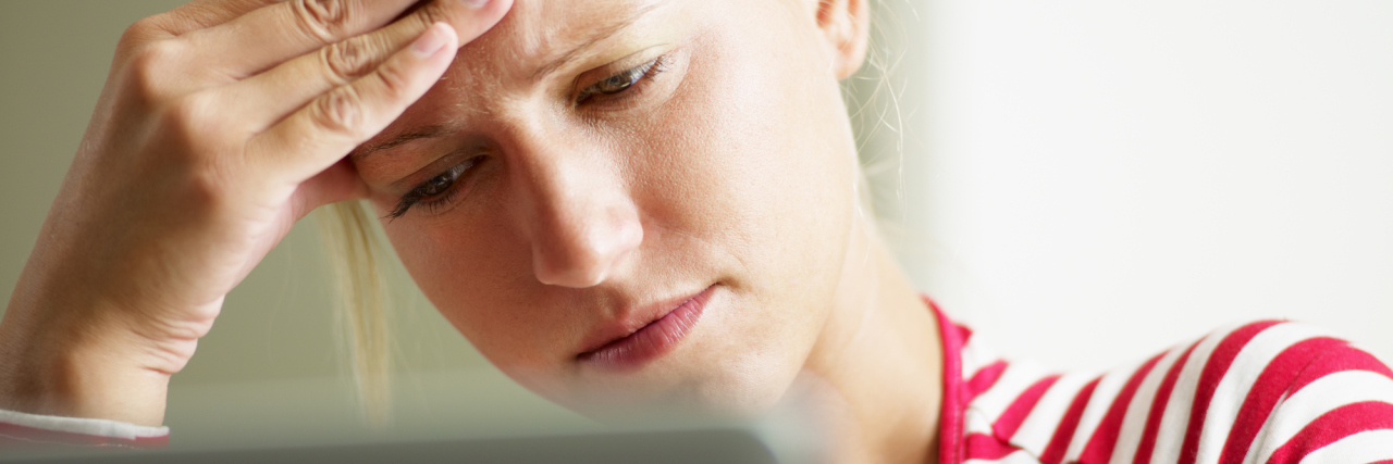 When Anxiety Makes You Feel Like a Burden on Your Workplace blonde woman with hand on forehead in front of computer looking upset or worried