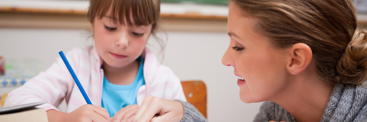 Things My Child’s Teacher Needs to Know About My Child With ASD Girl doing school work and teacher at eye level helping