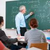 professor writing on chalkboard and teaching students