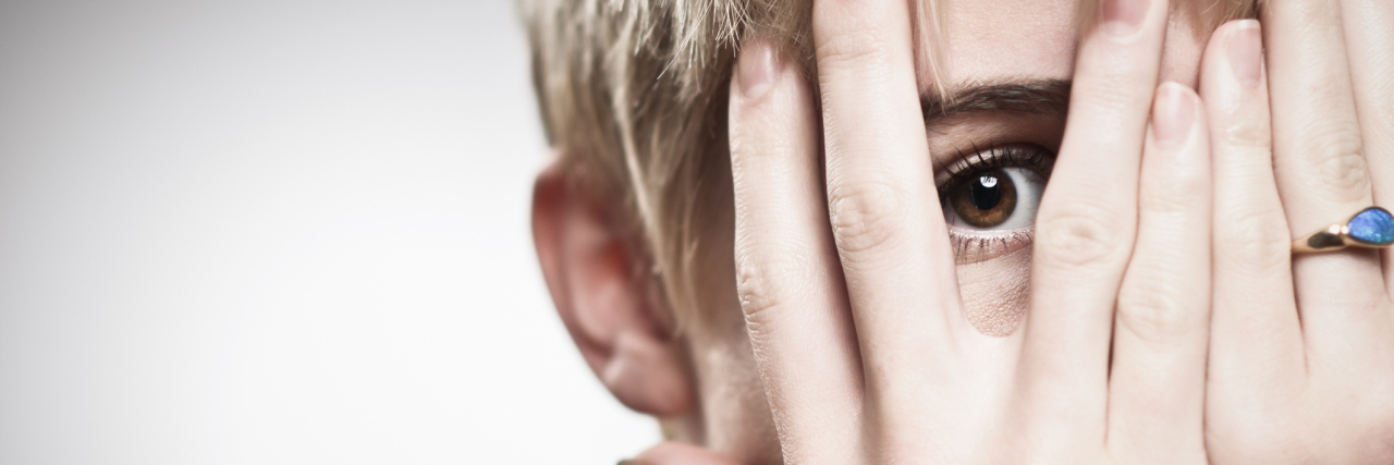 When You Can't Accept a Compliment Because of Your Mental Illness young woman with short blonde hair peeking through fingers
