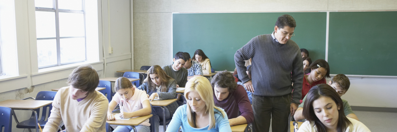 5 Ways Teachers Should Support Students With Anxiety and Depression Male lecturer looking at students writing in a classroom