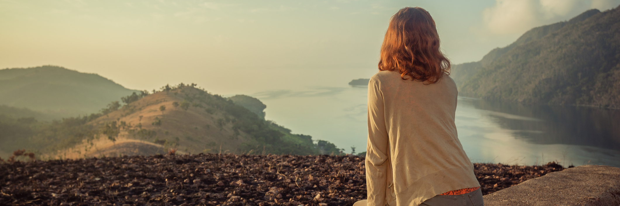 Coming to Terms With Life and Death After My Cervical Cancer Diagnosis Woman sitting on unusual rock at sunrise