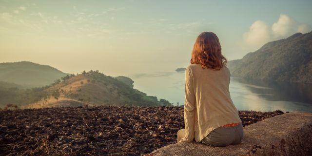 Coming to Terms With Life and Death After My Cervical Cancer Diagnosis Woman sitting on unusual rock at sunrise