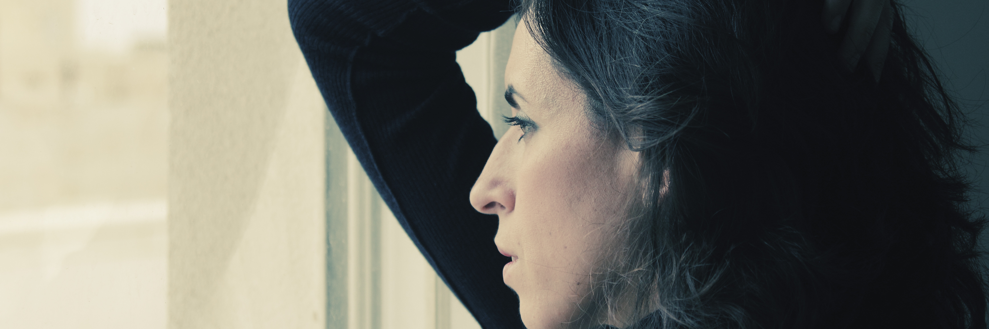Struggling With Mental Illness During the Summer woman stands in front of the window