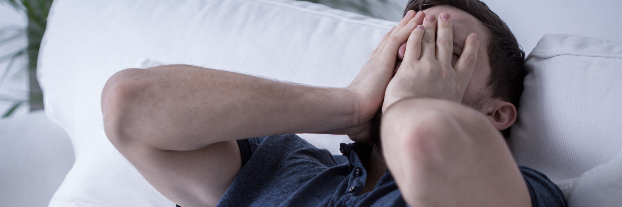 Struggling With Sleepiness, Nightmares of Narcolepsy for Many Years man lying in bed covering his face with his hands