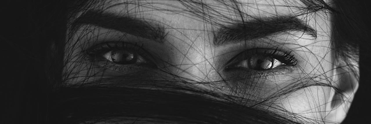 When You Feel Like You're Living in the 'Gray Area' of Rape Portrait of a mysterious woman with her long brown hair wrapped in strands across her face looking at the camera with seductive luminous eyes, monochrome head and shoulders image