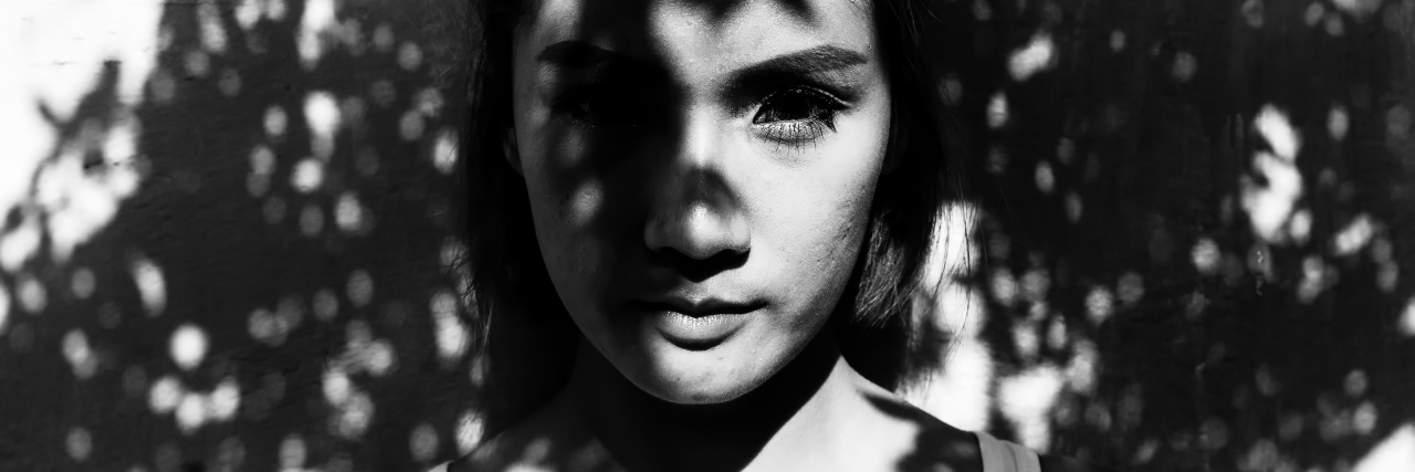 Understanding Why Someone Would Choose to Self-Harm Young woman standing in tree shadows Young woman