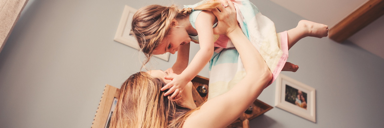 Eating Disorder: Having a Child Helped Me Accept my Body Woman holding her daughter up in the air