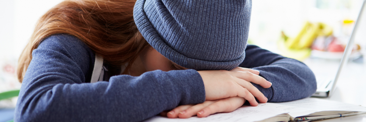 How to Help a Student With Obsessive-Compulsive Disorder upset girl with head on hands studying at home resting on book