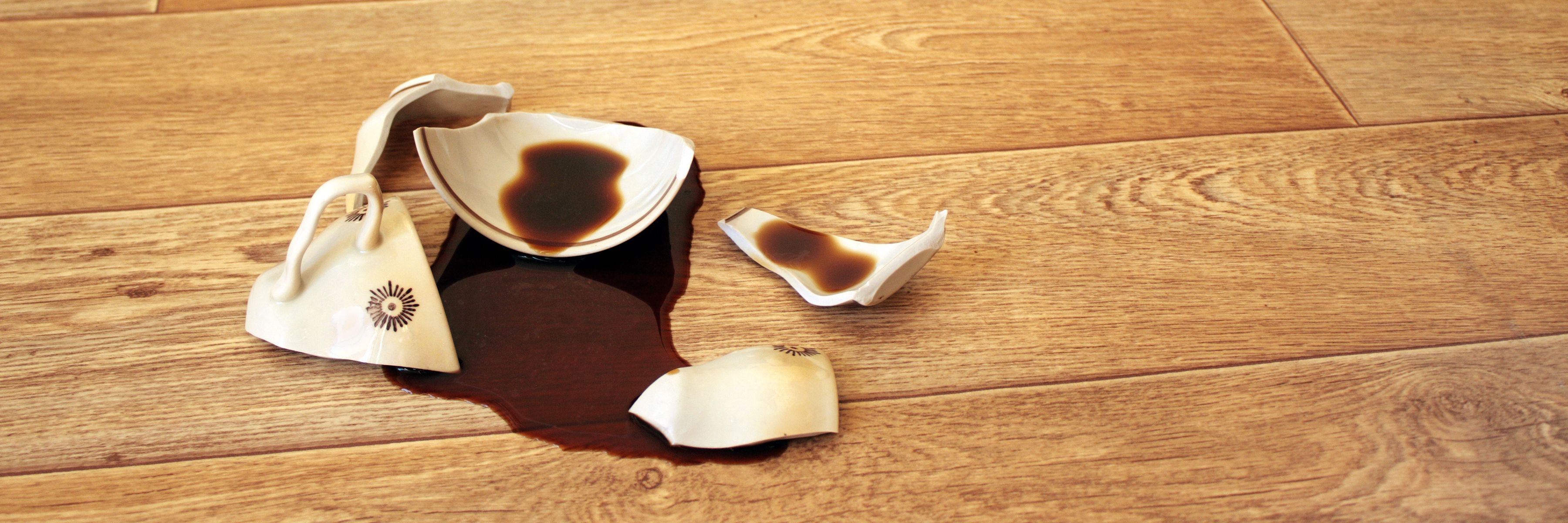 broken coffee mug on wooden floor with spilled coffee
