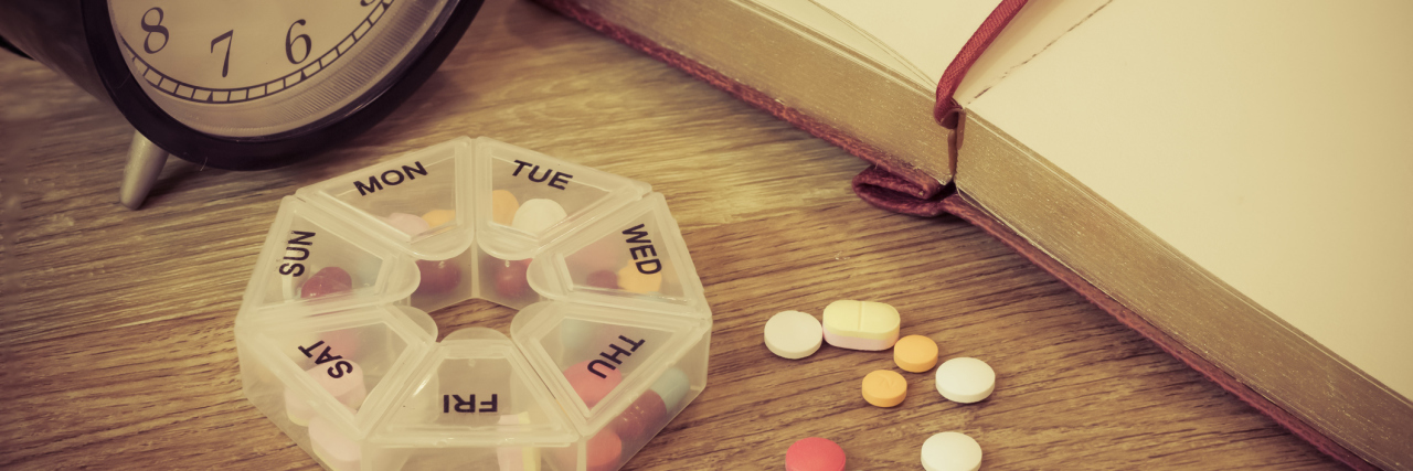 How I'm Accepting Life on Medication for My Anxiety and Depression daily pills and alarm clock with diary in vintage color concept