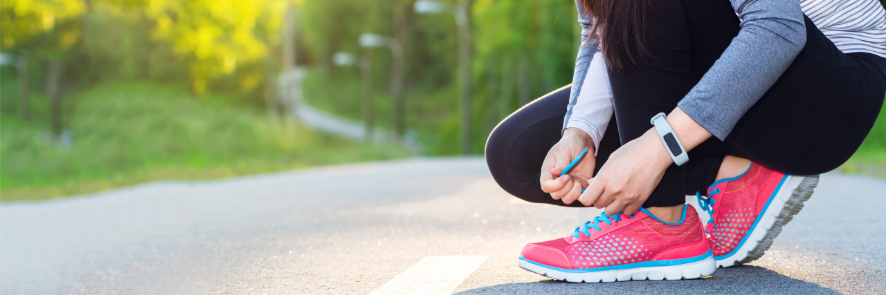 When You're a Runner With Chronic Illnesses A female runner tying her shoes.