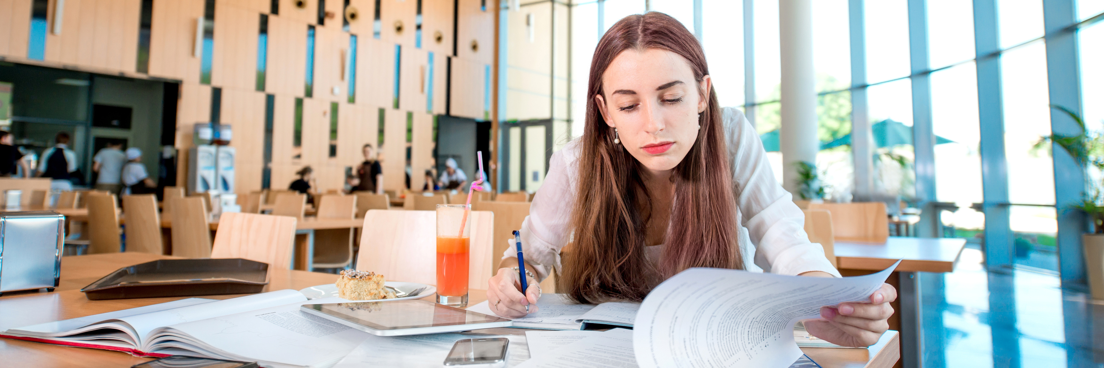 Girl studying in the University canteen with Fresh and cake