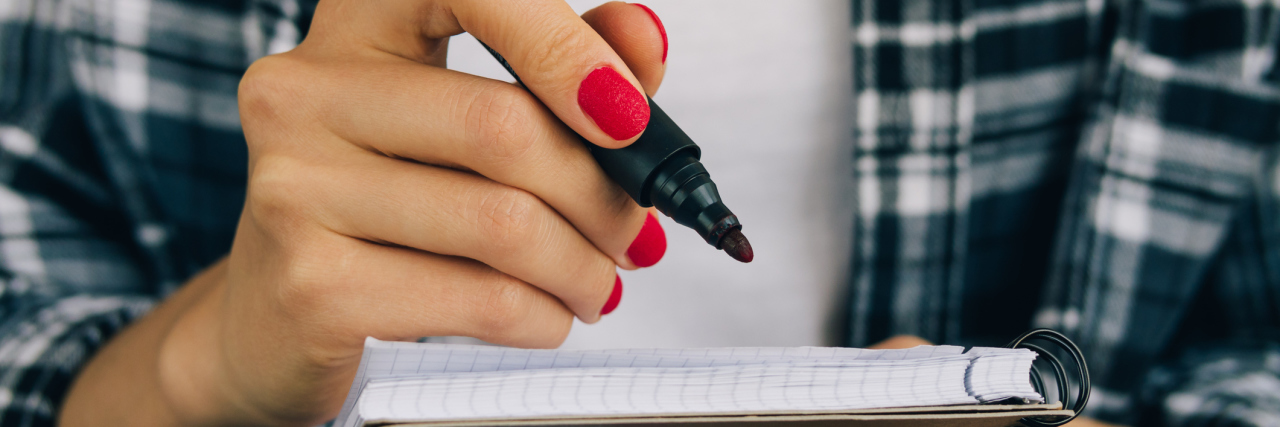 I Devised a 'Point System' to Tackle Everyday Tasks With Depression Woman in plaid shirt and red manicure felt pen writing in a notebook