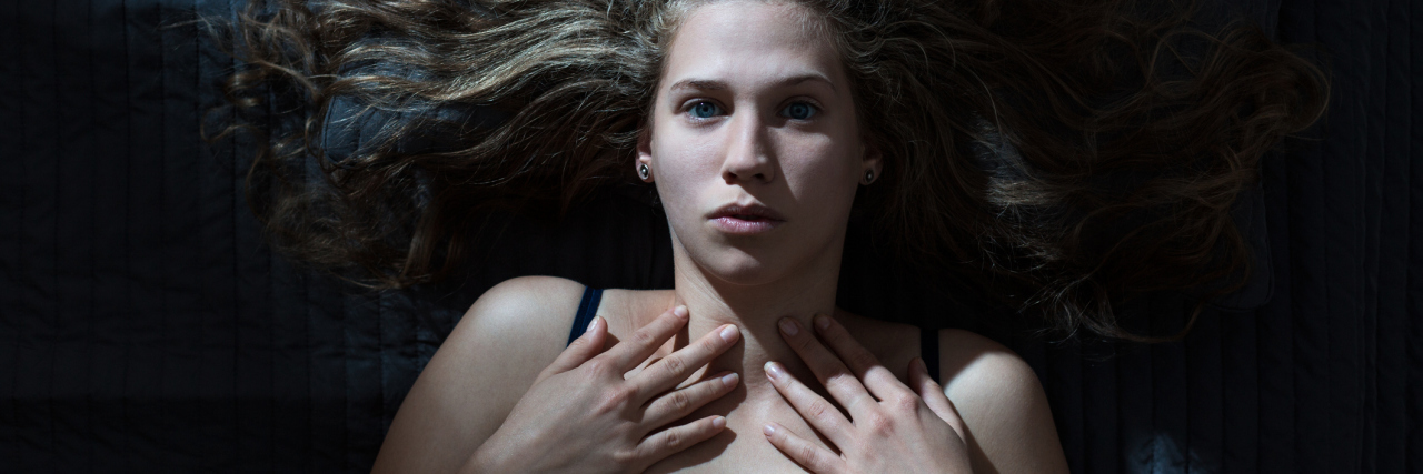 The Lies My Anxiety Tells Me at Night woman lying awake hands on chest afraid upset