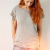 Young girl wearing grey blank t-shirt and blue jeans. Concrete white wall background, flare light