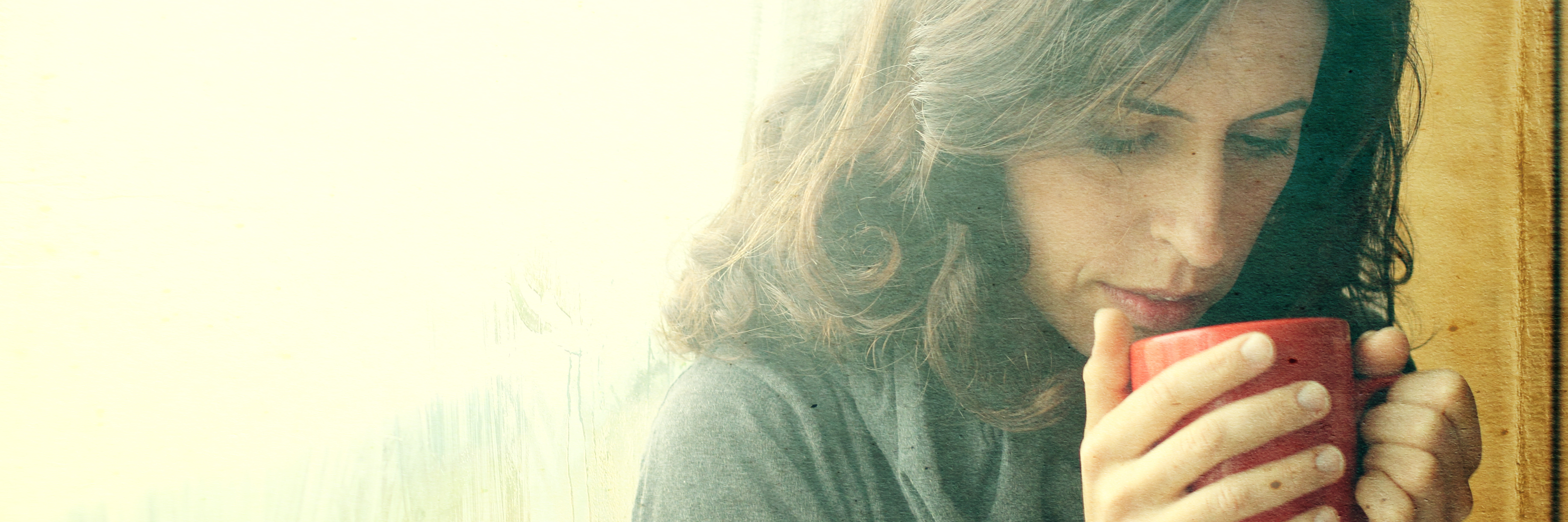 Feeling Bored by Lack of Recovery in Mental Illness mid 30s woman standing in front of window with red cup of tea or coffee