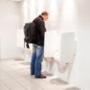 man standing at urinals