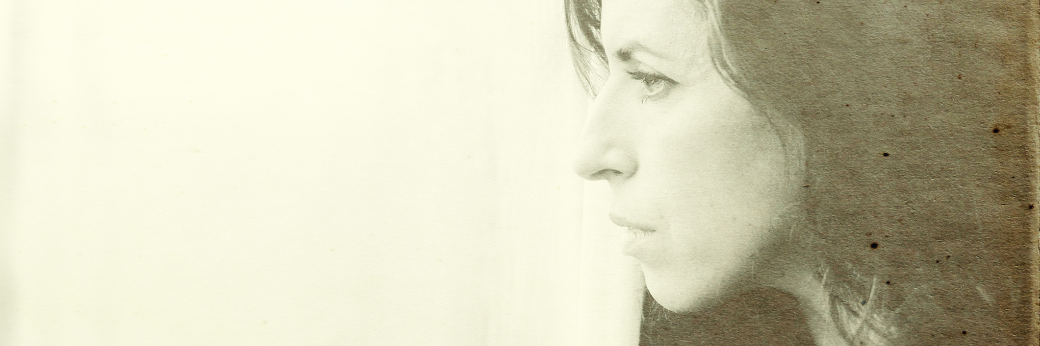 side view of woman looking out of window under sepia filter