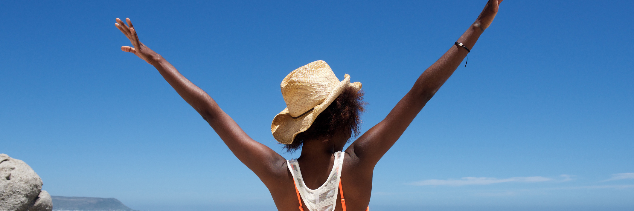 Young woman sitting on beach with her hands outstretched