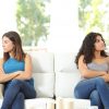 two friends sitting on opposite ends of the couch with arms crossed looking away from each other