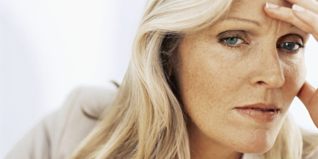 Why I Feel Like a Chronically Ill Underdog A woman holding her head in her hand, looking frustrated.