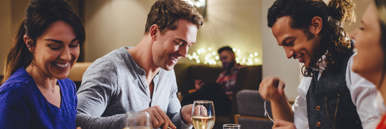 Why Double Dating Is Difficult for Me as Someone With Anxiety Group of friends enjoying an evening meal with wine at a restaurant.