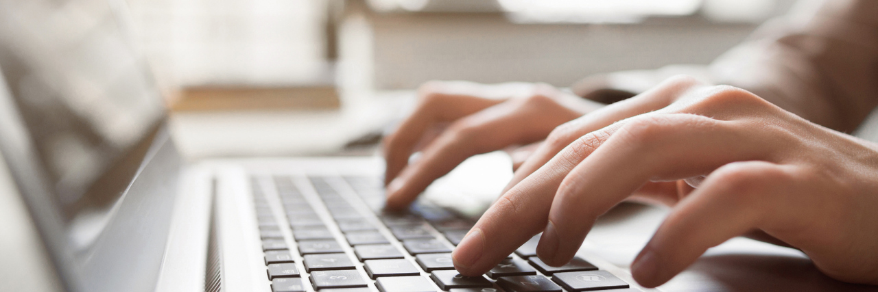 Coming Out About My Invisible Disability Typing on laptop closeup.