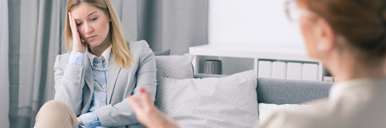What You Need to Know About Seeing a Therapist young blonde woman looking upset in session with older therapist